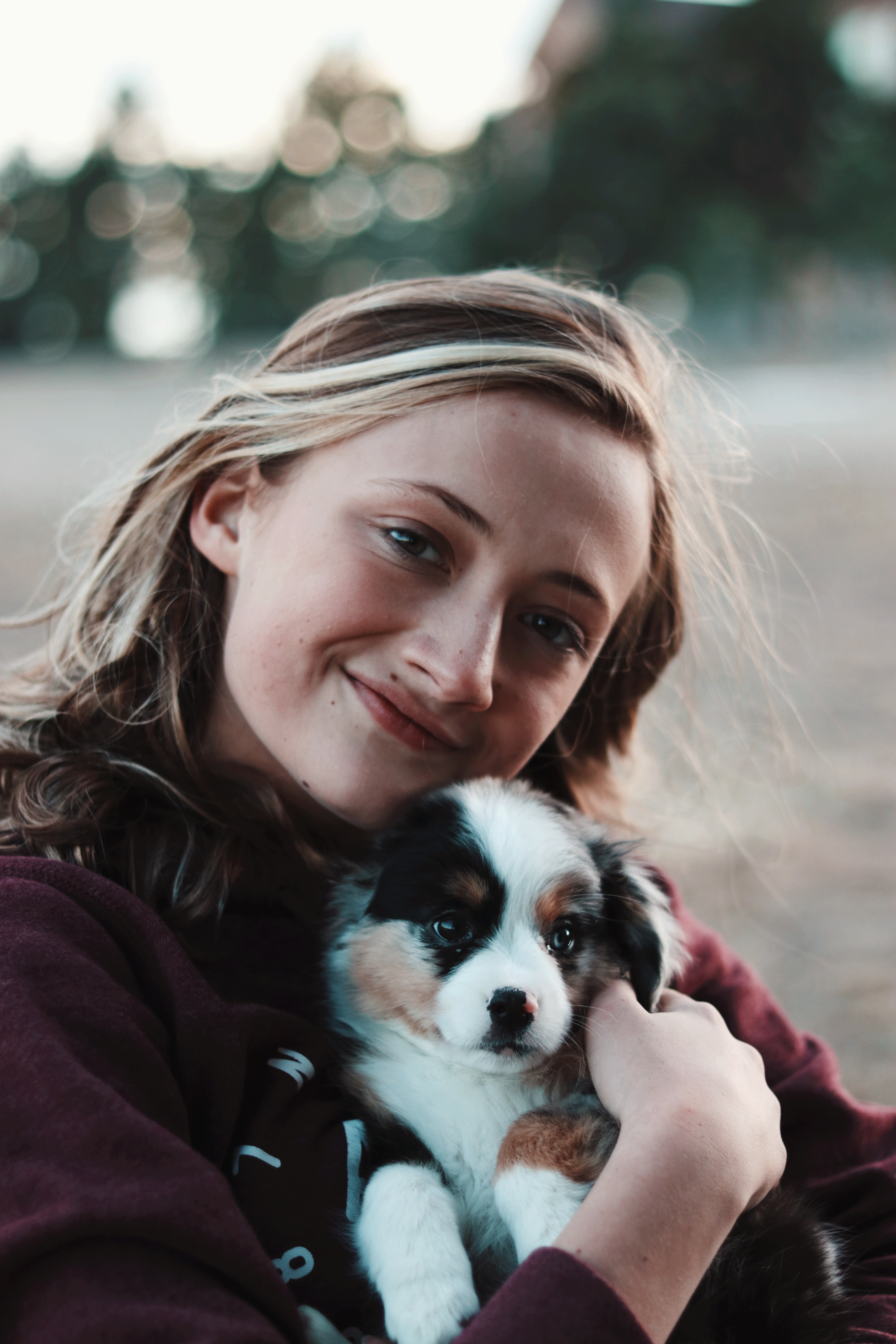 The image in the section that begins with the text “like a best friend” is a picture of a pretty young lady with long, flowing light brownish red hair with light blonde hair streaks, perhaps in her late 20s to early 30s, holding what appears to be an Australian sheepdog very young puppy to her chest with a warm, loving smile with her head tilted to hug the puppy. 